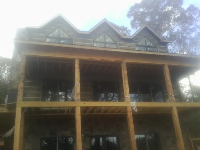 Dormers and porch framing on a large log home under construction — Roof Coating work by our crew in Tannersville